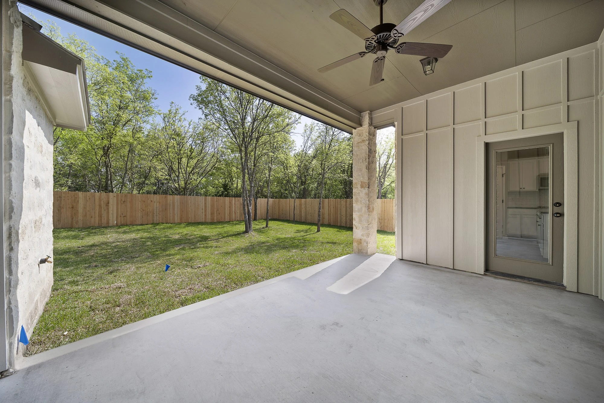 Covered outdoor living area opening to mature Central Texas trees