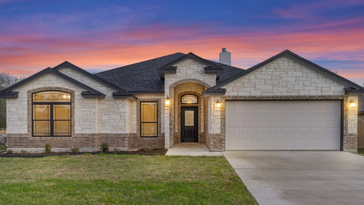 Brick and limestone home with a warm illuminated entry